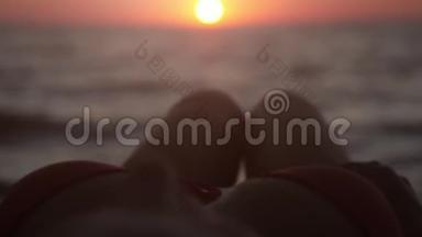 放松的年轻女孩躺在热带海滩上。 在日落时伸直腿。 慢动作。 1920x1080